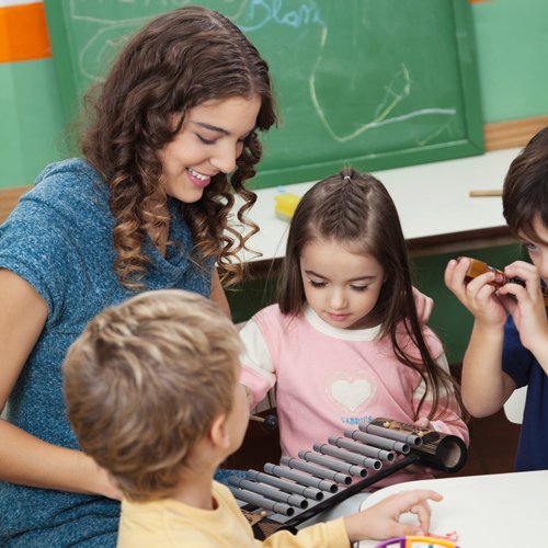 Smiling teacher shows young studnets a xylophone