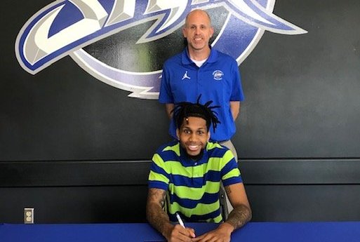 Basketball player signing paper with coach standing behind