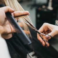 hands with scissors and comb styling someones hair