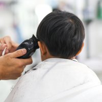young child gets haircut with clippers