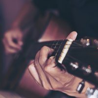 Closeup of person holding guitar.