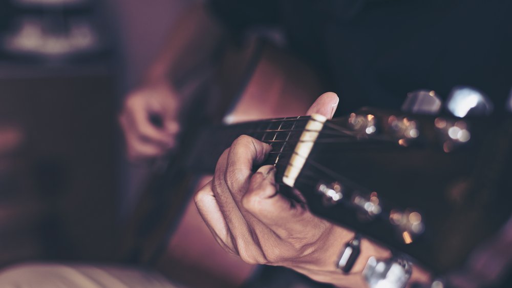 Closeup of person holding guitar.