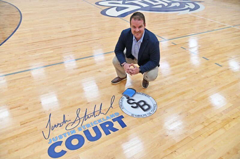 Justin Strickland kneeling beside his name on Brinkley Gym floor