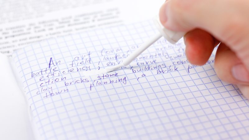 hand uses whiteout to remove text from page