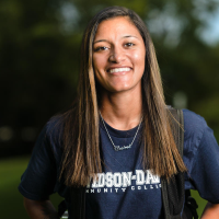 Outdoor photo of smiling student wearing a navy Davidson-Davie t-shirt.