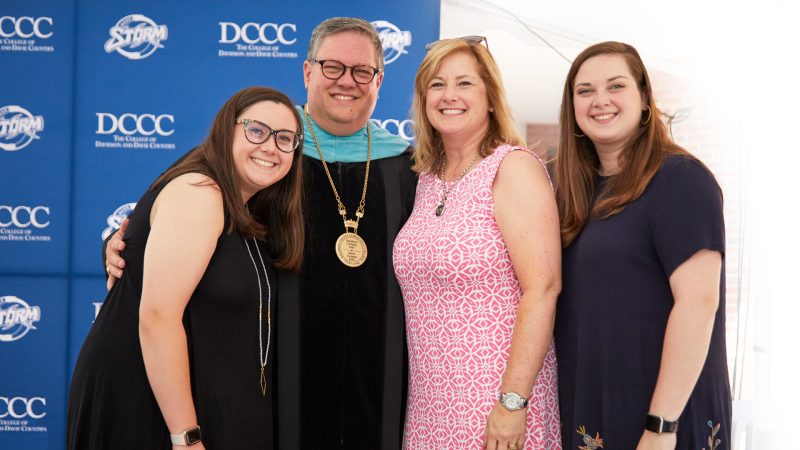 Dr. Darrin Hartness and family posing in from of blue backdrop.