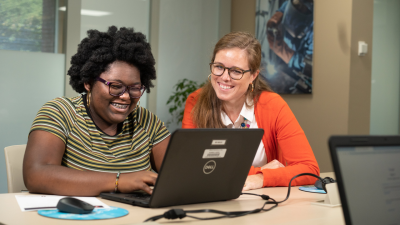 Admissions staff helps student apply on laptop