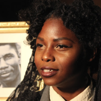 woman sits in front of framed black and white photo of man