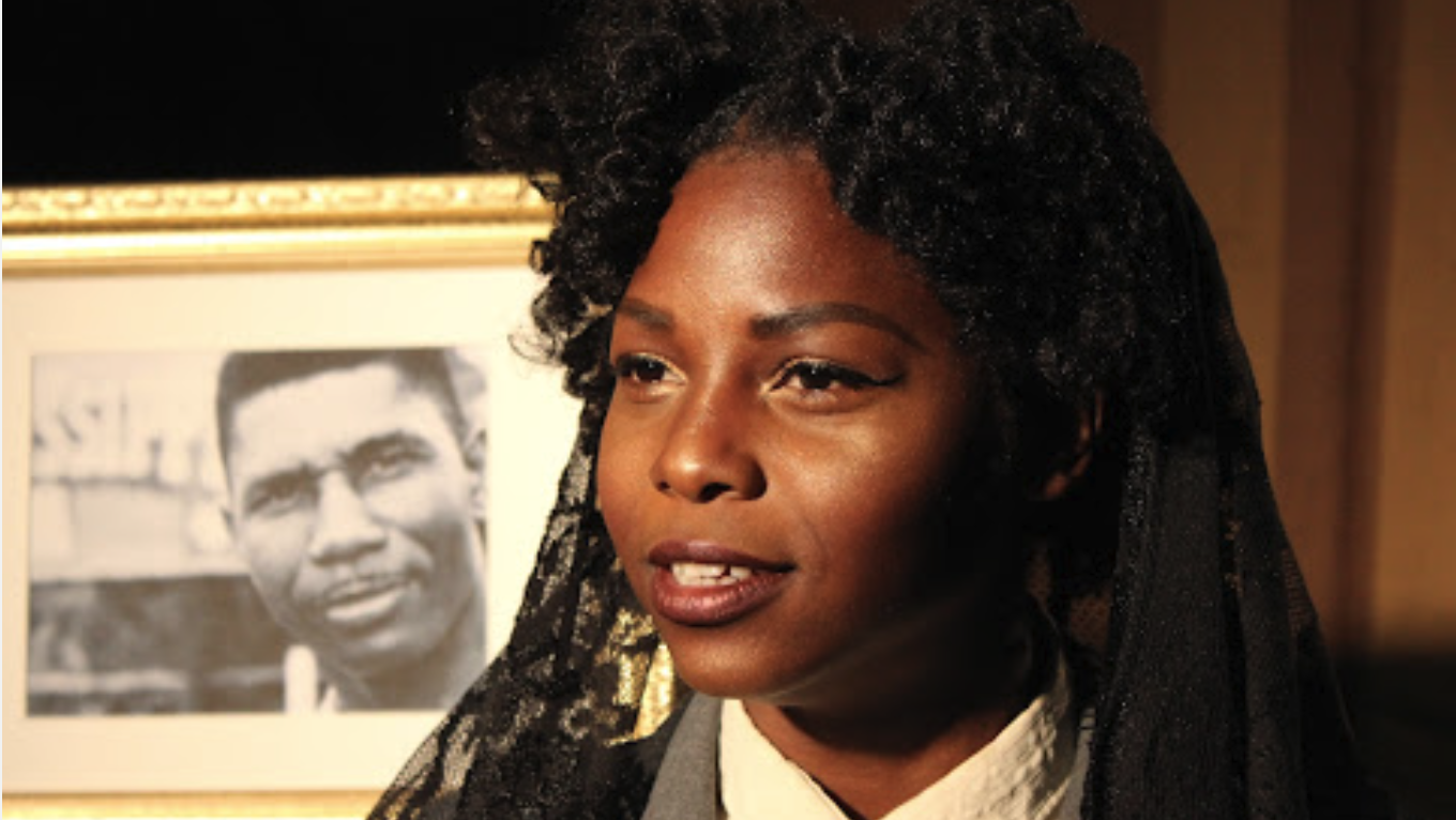 woman sits in front of framed black and white photo of man