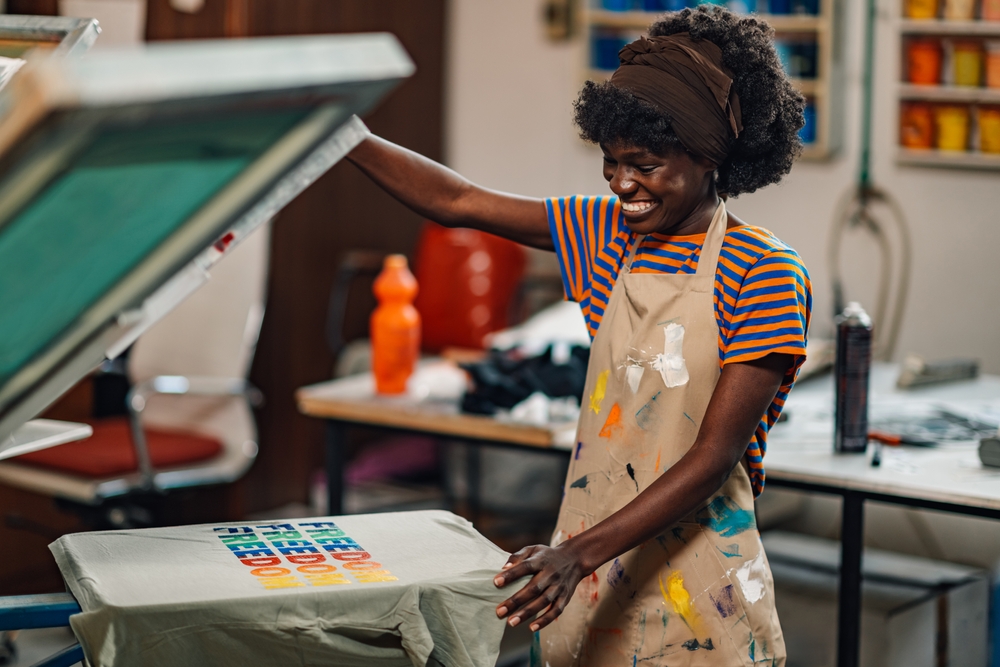 young girl smiling while screen printing a shirt