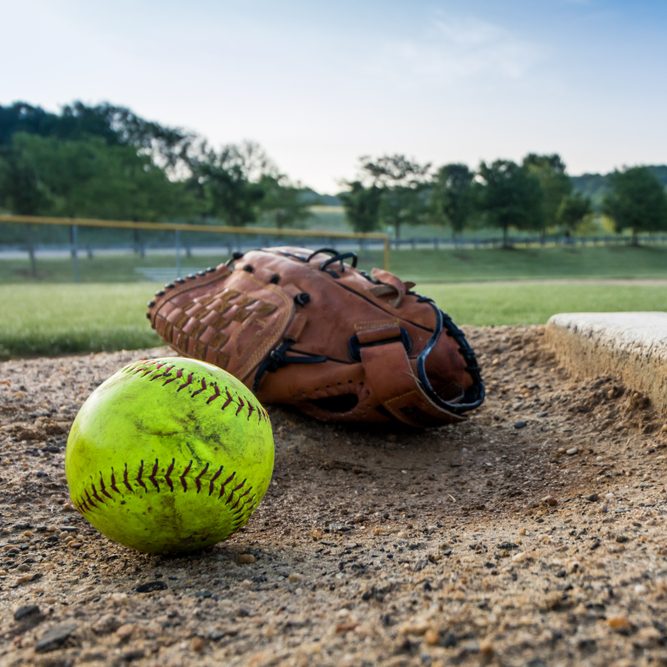 Worn softball and glove on pitcher's mound in early morning