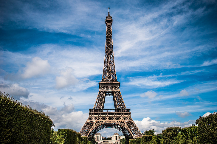 Eiffel Tower in Paris against a blue sky with clouds.