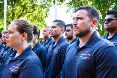 A group of people wearing matching dark blue polo shirts with "Davidson-Davie Community College" logos, standing outdoors under trees.