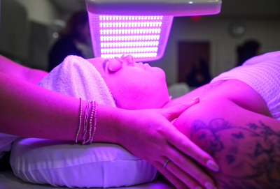 Person receiving LED light therapy on their face under a purple light panel.