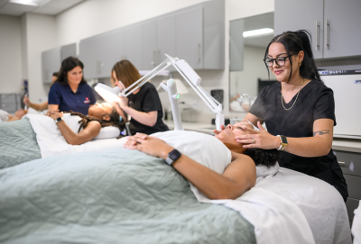 Two people receiving facials in a spa setting, with therapists attending to them.