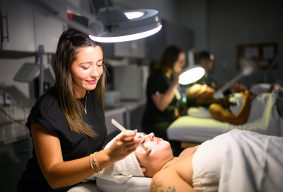 A woman applying a facial treatment to a client in a salon setting.