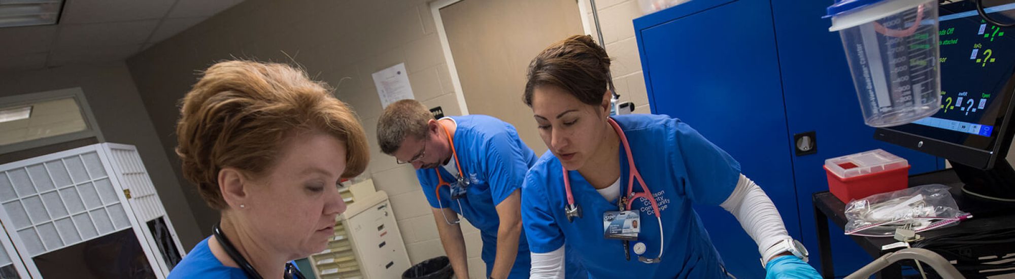Nurses in blue uniforms working with patient on hospital bed