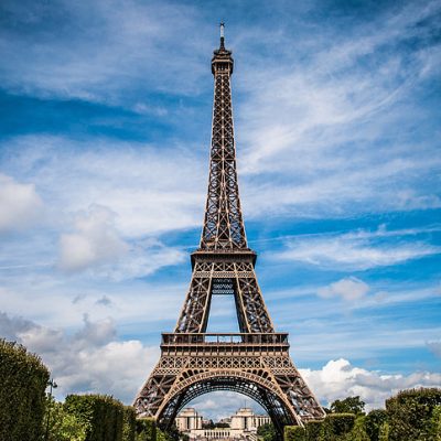 Eiffel Tower in Paris against a blue sky with clouds.