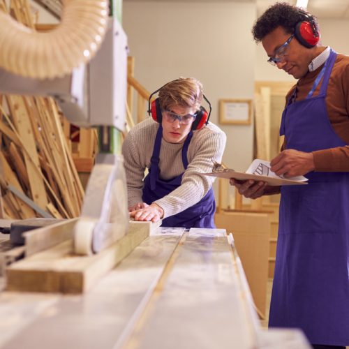 Tutor,With,Male,Carpentry,Student,In,Workshop,Studying,For,Apprenticeship Young men doing carpentry work in wood shop