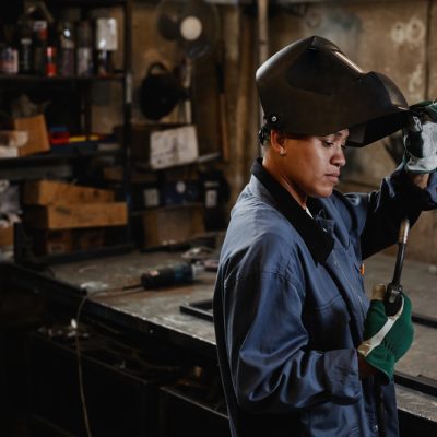 Side,View,Portrait,Of,Woman,Welder,Inspecting,Tools,In,Industrial Side view portrait of woman welder inspecting tools in industrial workshop