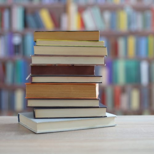 Stack,Of,Books,On,Wooden,Table,In,Library stack of books on wooden table in library