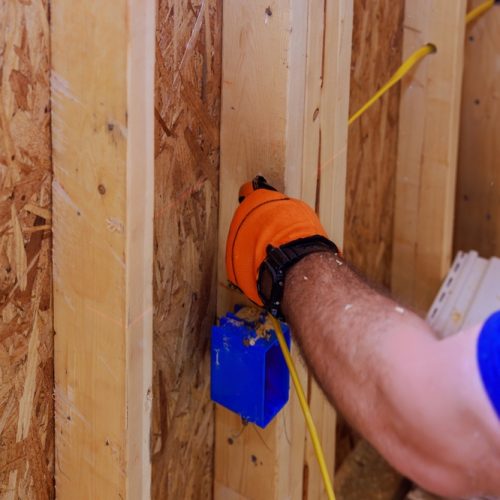 Electrician,Installs,Electrical,Wires,On,Site,During,Construction,Of,Residential Electrician installs electrical wires on site during construction of residential building