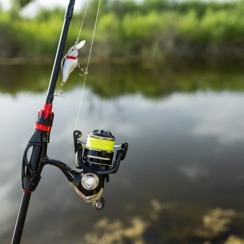 Close-up,Of,Fishing,Rod,Reels.,Fishing,On,The,Shore,Of Close-up of fishing rod reels. Fishing on the shore of the lake. Spinning rods for sport fishing.