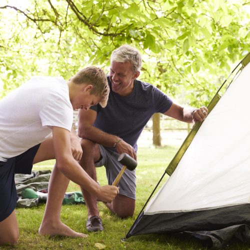 Father,And,Teenage,Son,Putting,Up,Tent,On,Camping,Trip Father And Teenage Son Putting Up Tent On Camping Trip
